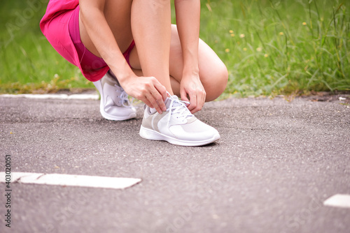 Young woman runner tying shoelaces with copy space, healthy lifestyle and sport concepts.