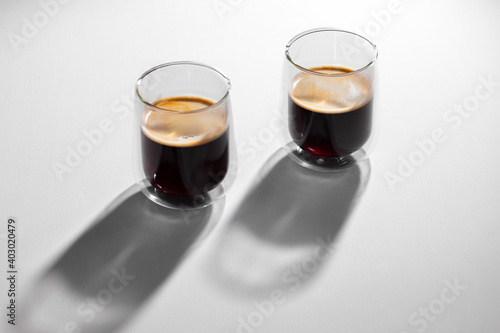 Americano coffee in glass cups on white background with long shadows