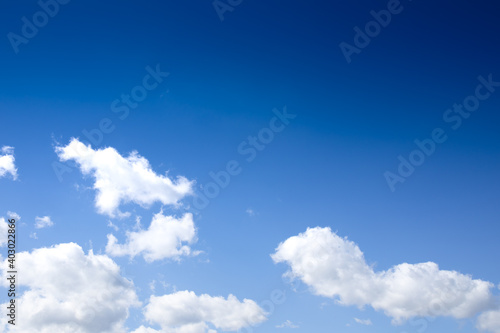 Gradient deep to bright blue sky with puffy white clouds  creative copy space  horizontal aspect