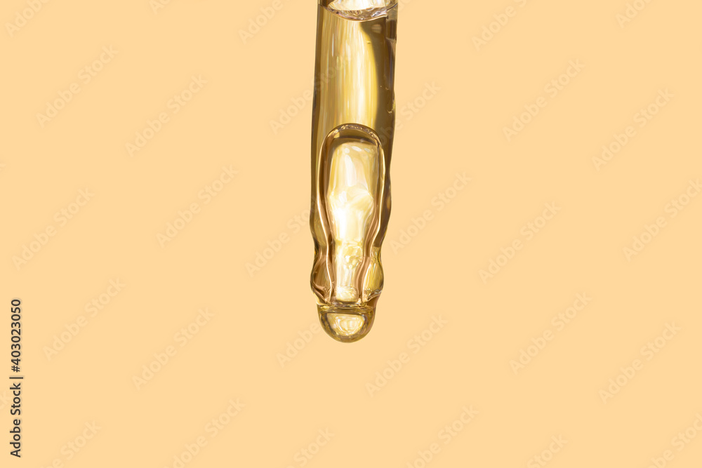 detail of gold pipette dropper with beauty serum on a beige background detail of gold pipette dropper with beauty serum on a beige background