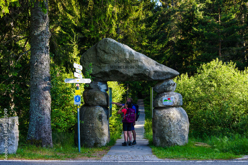 Two hikers standing at an recreation area entry looking for orientation with the help of a stationary hiking map. photo