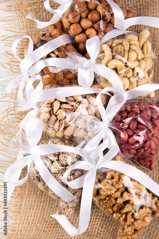 set of nuts in a gift transparent packaging tied with a white ribbon on a burlap on a white background