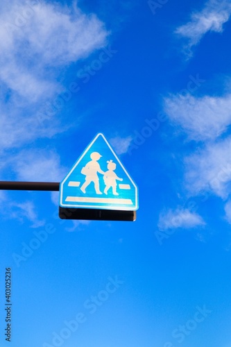 青空と子どもが通学で渡る横断歩道ありの標識