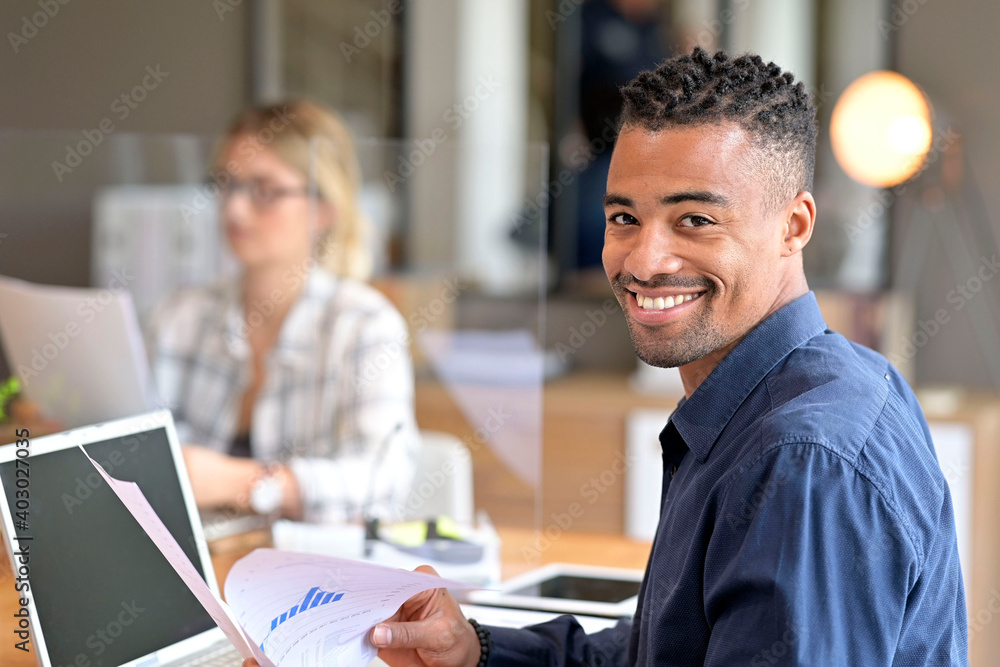 Fototapeta premium Multiracial staff at work in co-working office separated with plexiglas protection