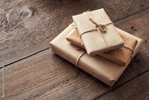Christmas presents wrapped in ecological recycled paper on a wooden table with copy space