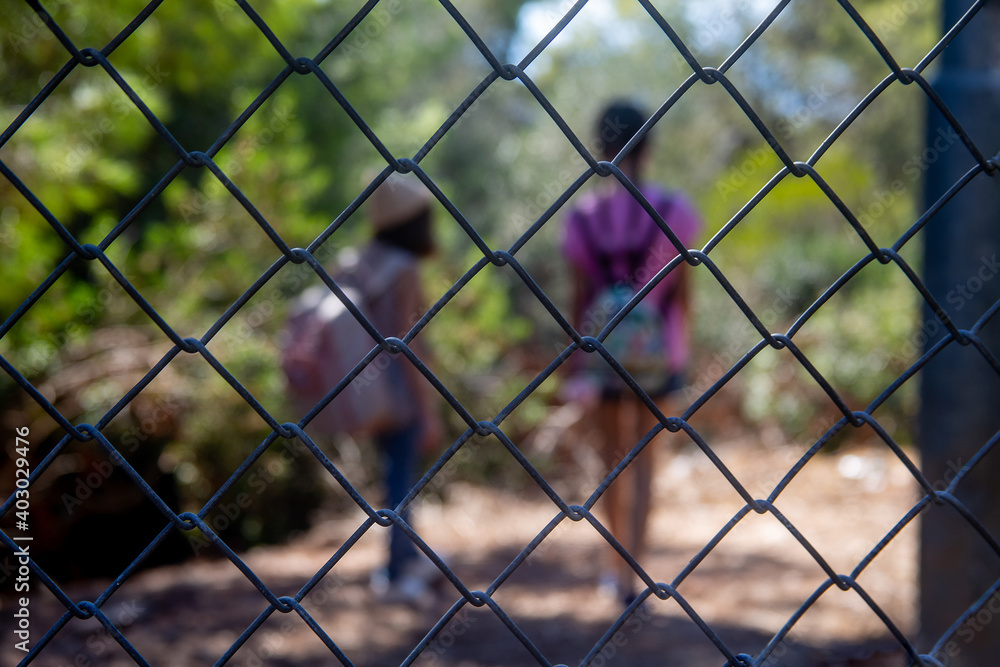 Children (two girls) are behind bars. they stand and stare into the distance, children in blur Children (two girls) are behind bars. they stand and stare into the distance, children in blur