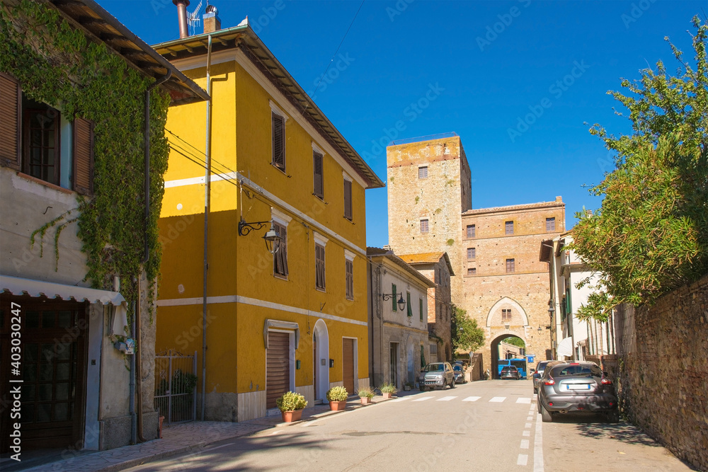  A street in the historic medieval village of Paganico near Civitella Paganico in Grosseto Province, Tuscany, Italy. Part of the city walls can be seen in the background