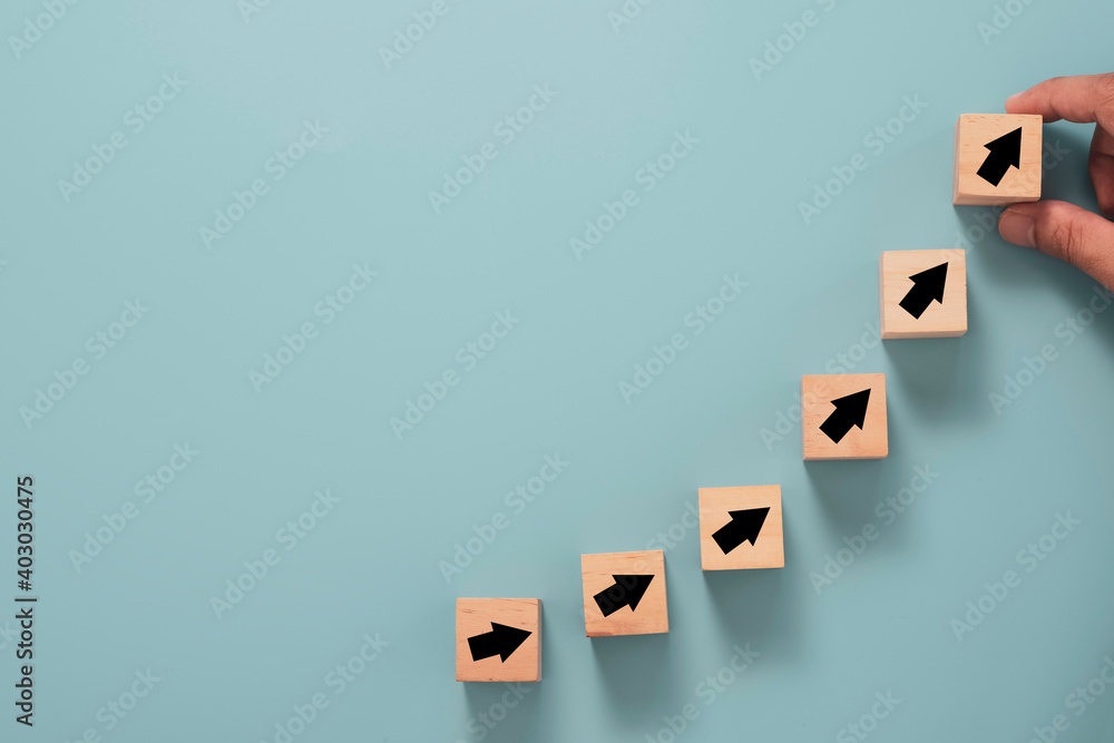 Business investment growth concept , Businessman holding wooden cube block which print screen up and increase black arrow on blue background. Business investment growth concept , Businessman holding wooden cube block which print screen up and increase black arrow on blue background.