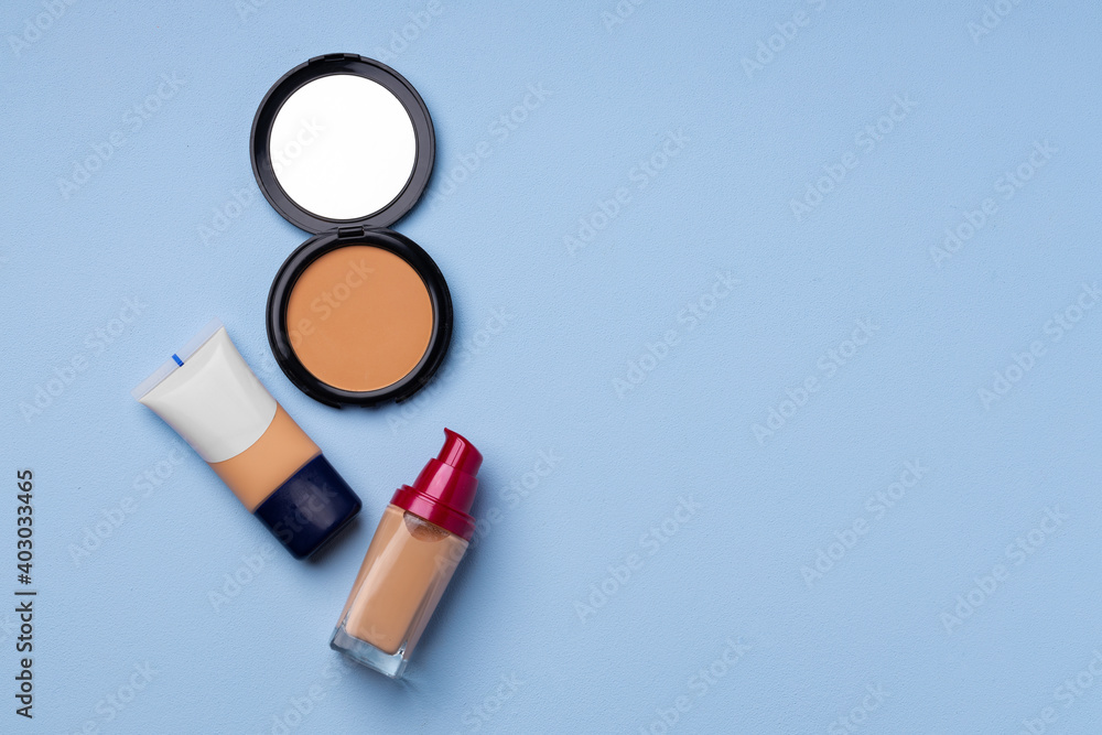 Complexion make up products and brush on blue background Complexion make up products and brush on blue background