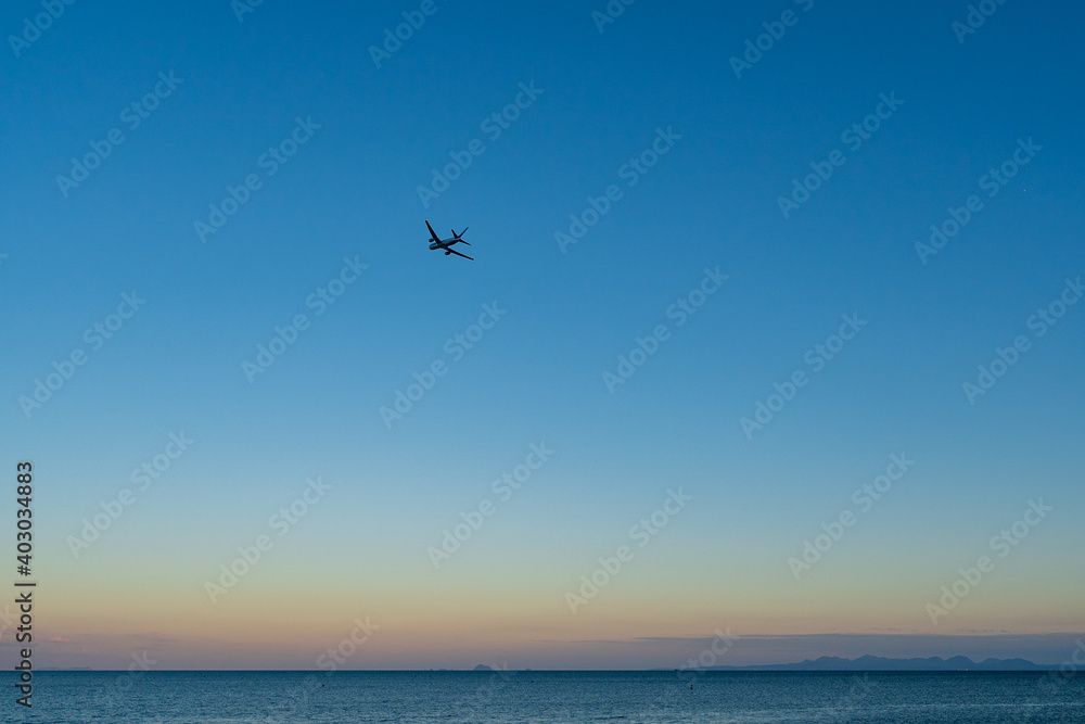 夕暮れ時の空を上昇していく飛行機