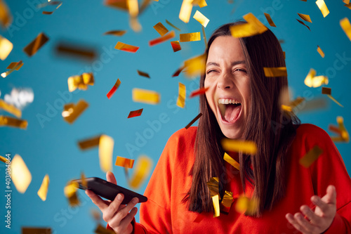 Foto Celebrating Young Woman With Mobile Phone Winning Prize And Showered With Gold C