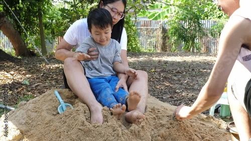4K Authentic asian family playing sand on foot together outdoor in nature with smiling face. Child, mother, father having happy moment time in summer. Concept of family activity, good relationship.