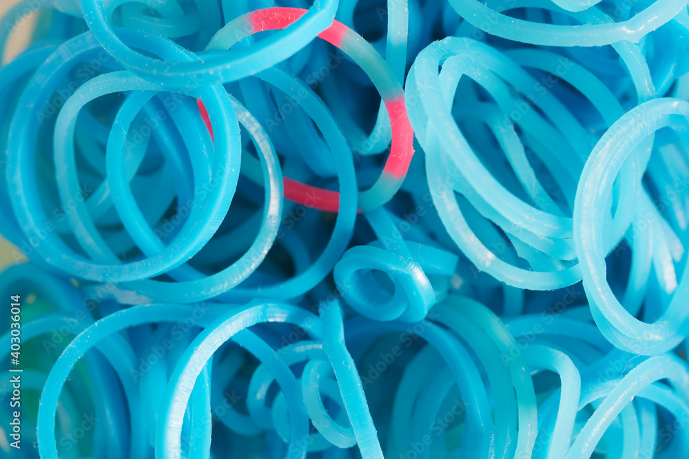 A set of light blue elastic bands for weaving bracelets or charms. Children's hobby and handicraft. Subject for the development of fine motor skills of hands. Close-up. Macro.