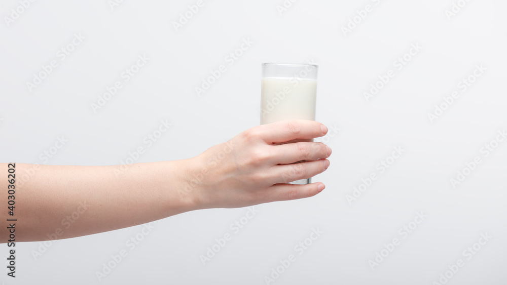 Naked female hand holding transparent glass of milk over white background. Naked female hand holding transparent glass of milk over white background.
