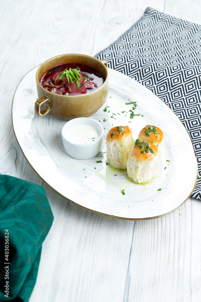 Bowl of national Ukrainian or Russian red vegetable and meat soup with garlic rolls of donuts and sour cream Bowl of national Ukrainian or Russian red vegetable and meat soup with garlic rolls of donuts and sour cream