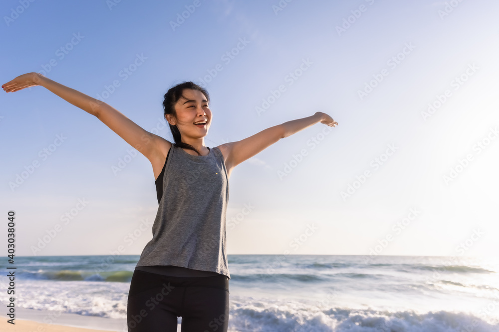 Beautiful Asian sporty girl smiling stretching hands warmup for running on beach in morning Beautiful Asian sporty girl smiling stretching hands warmup for running on beach in morning