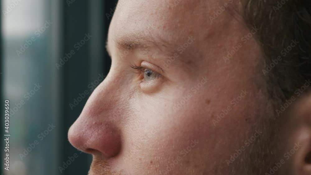 Close-up Portrait of a young man looking into the distance. Blue eyes of a young guy macro, natural beauty. The young guy blinks, dreams. Side view, in profile, slow motion Close-up Portrait of a young man looking into the distance. Blue eyes of a young guy macro, natural beauty. The young guy blinks, dreams. Side view, in profile, slow motion