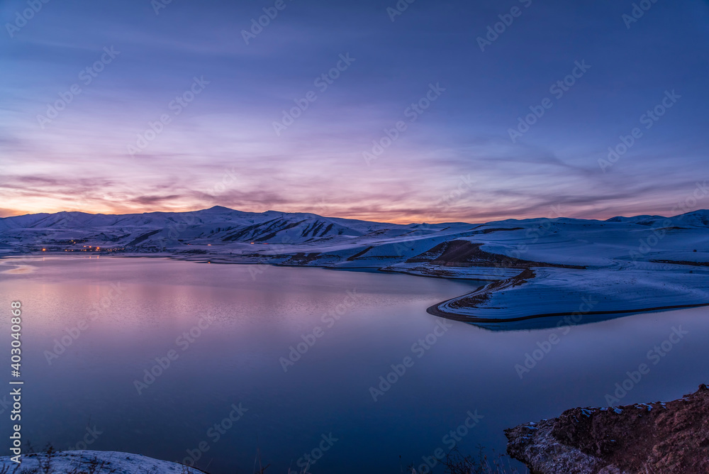 Beautiful winter landscape. Panoramic view on the lake  and mountains peaks snow-covered  after sunset. 