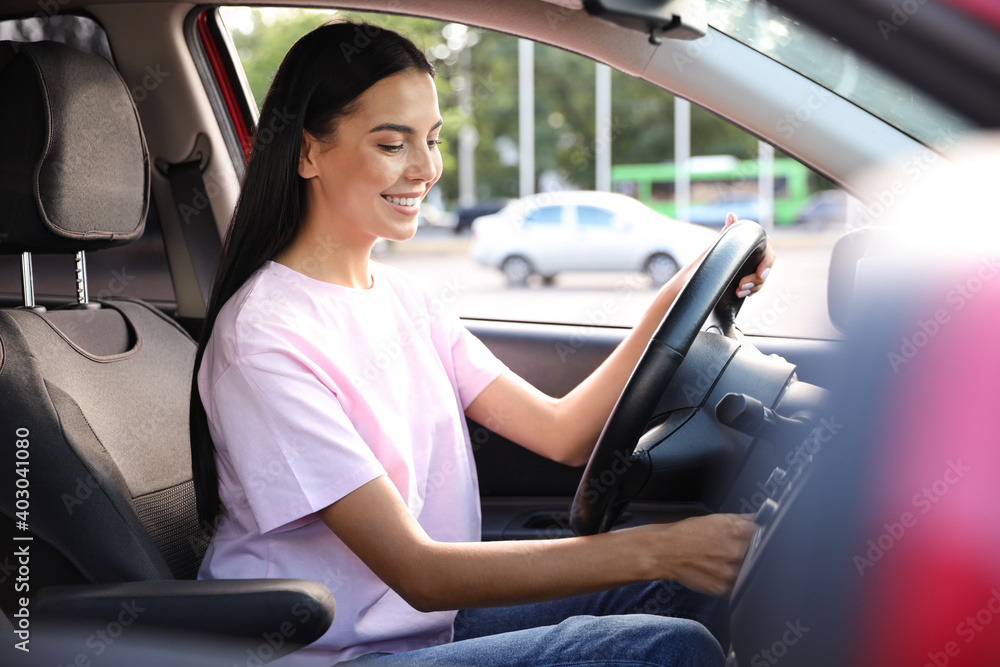 Young woman starting engine of car. Driving school