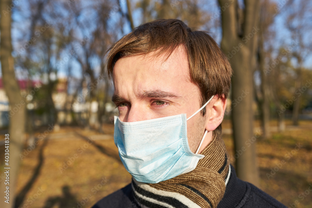 Closeup portrait of a young guy in a disposable medical mask. Pandemic. Coronavirus. Quarantine. The young man in the mask. Closeup portrait of a young guy in a disposable medical mask. Pandemic. Coronavirus. Quarantine. The young man in the mask.
