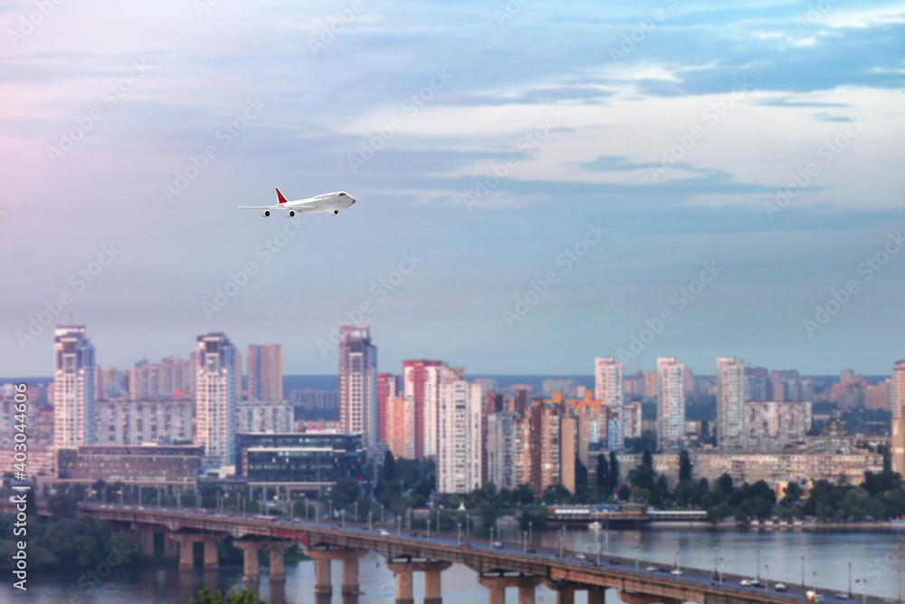 Modern airplane flying in cloudy sky over city Modern airplane flying in cloudy sky over city