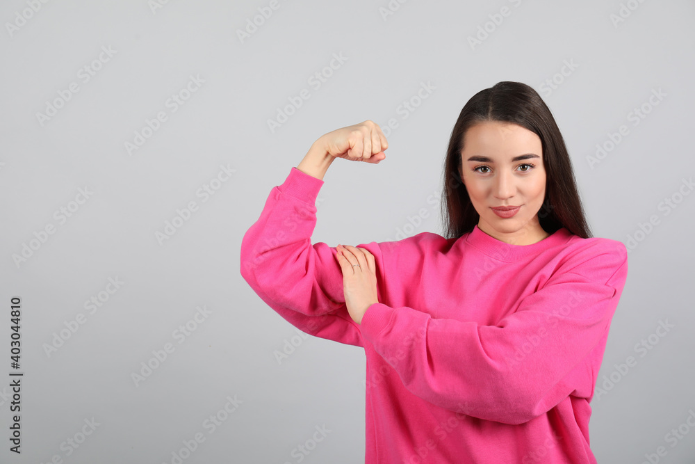 Strong woman as symbol of girl power on light grey background, space for text. 8 March concept Strong woman as symbol of girl power on light grey background, space for text. 8 March concept