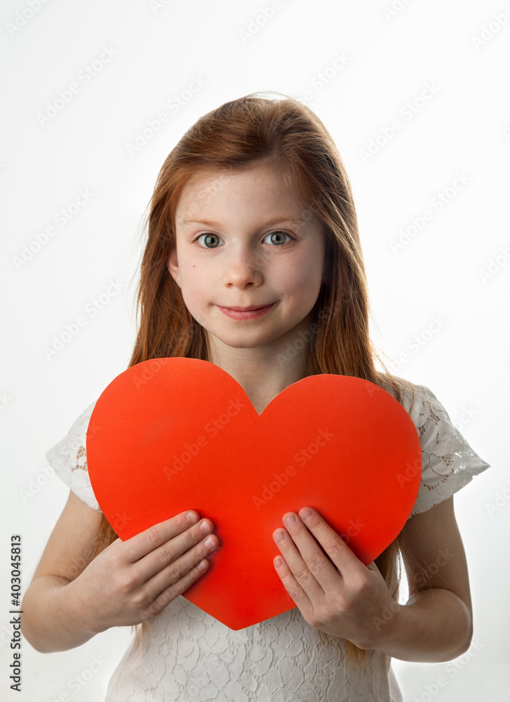 Portrait of smiling red-haired little girl holding big red heart in her hands on white background. Love, Valentines Day, Mothers Day or Fathers Day concept. Portrait of smiling red-haired little girl holding big red heart in her hands on white background. Love, Valentines Day, Mothers Day or Fathers Day concept.