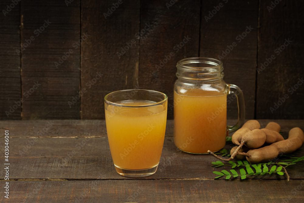 Tamarind juice in glass and tamarind fresh tropical fruit with leaf on wooden background. Tamarind juice in glass and tamarind fresh tropical fruit with leaf on wooden background.
