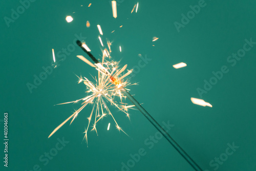 Fotografija Sparkler lit burning down on a tidewater green color background