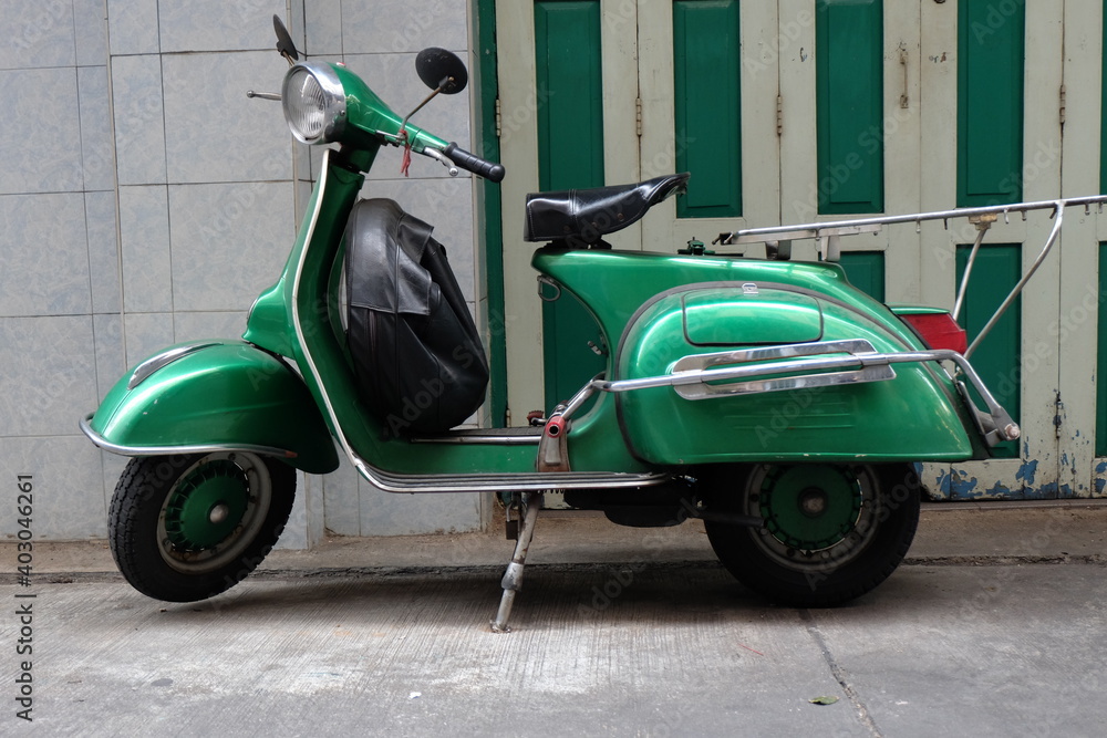 A Vespa car parked in front of a house in Bangkok. It is also a very popular car in Thailand.