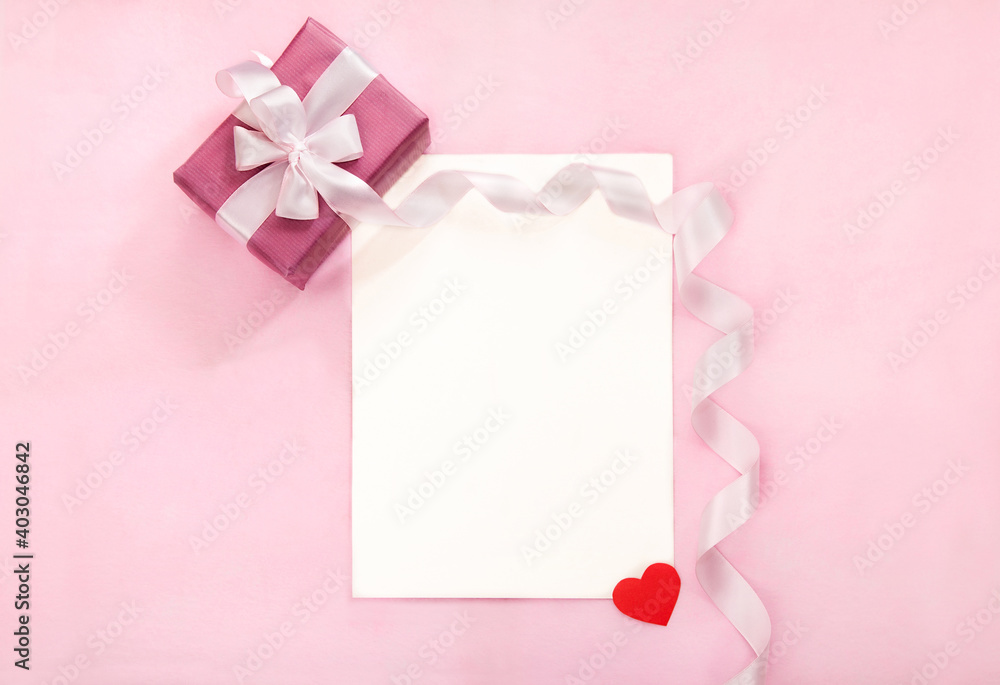 Valentines day greeting card with pink gift box, white bow, long curved ribbon and paper red heart. Tope view, empty space for text Valentines day greeting card with pink gift box, white bow, long curved ribbon and paper red heart. Tope view, empty space for text