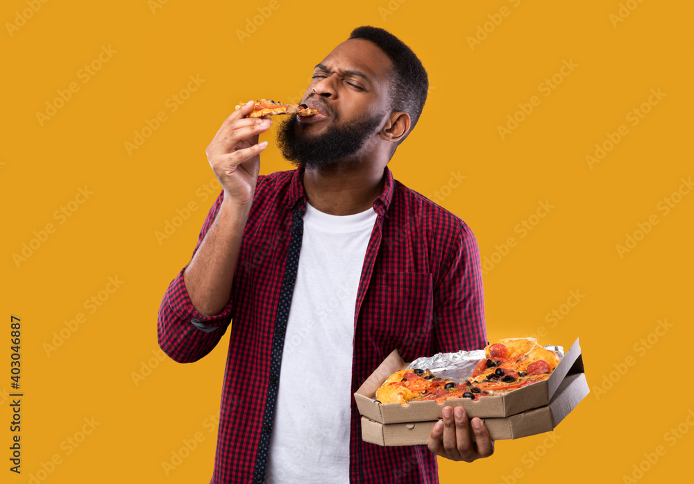 African American Man Enjoying Eating Pizza Standing Over Yellow Background African American Man Enjoying Eating Pizza Standing Over Yellow Background