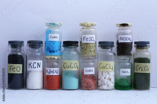 Glass jars with different colored inorganic reagents, with chemical formulas. photo