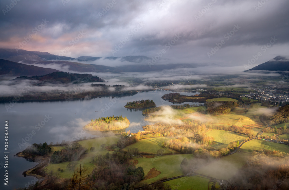Atmospheric early light shining on Derwentwater in the Lake District on a misty morning