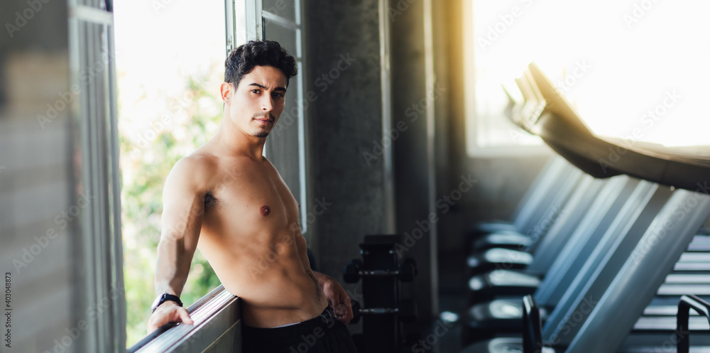 Portait Handsome young man while resting at gym. Man training in a gym Fitness.workout, exercises and healthy concept Portait Handsome young man while resting at gym. Man training in a gym Fitness.workout, exercises and healthy concept