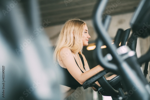 portrait of fitness young woman in sports clothing and exercising on bicycle at the fitness center