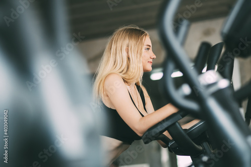 portrait of fitness young woman in sports clothing and exercising on bicycle at the fitness center