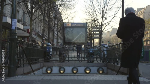 Two men walk to steps leading down to the Metro in Paris, France