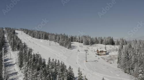 Skiers going downhill on Kope ski resort Ribnica One track in Slovenia, Aerial dolly left shot