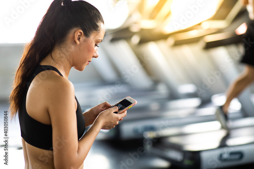 Active woman athlete taking rest and use smartphone after exercising at gym. Fitness Healthy lifestye and workout at gym concept. photo