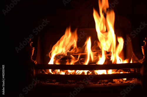 Closeup of dancing flames with dark background of burning wooden logs in fireplace, warming light in Christmas holidays