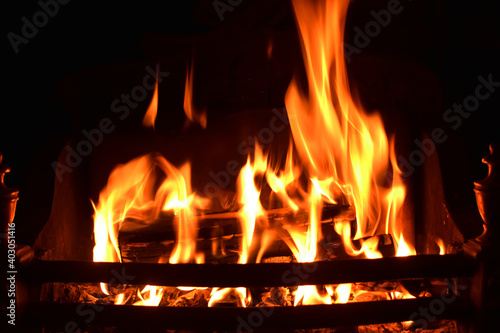 Closeup of dancing flames with dark background of burning wooden logs in fireplace  warming light in Christmas holidays