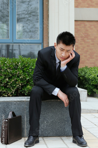 A business man is sitting outside thinking