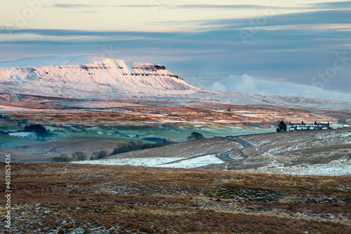 Pen-y-ghent covered in snow with beautiful Winter evening sunlight. Yorkshire Dales National Park, UK.