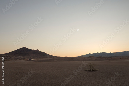 panoramic view death valley  desert with car and some mountains on the back during sunset