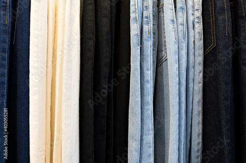 A row of various color jeans trousers grouped by color