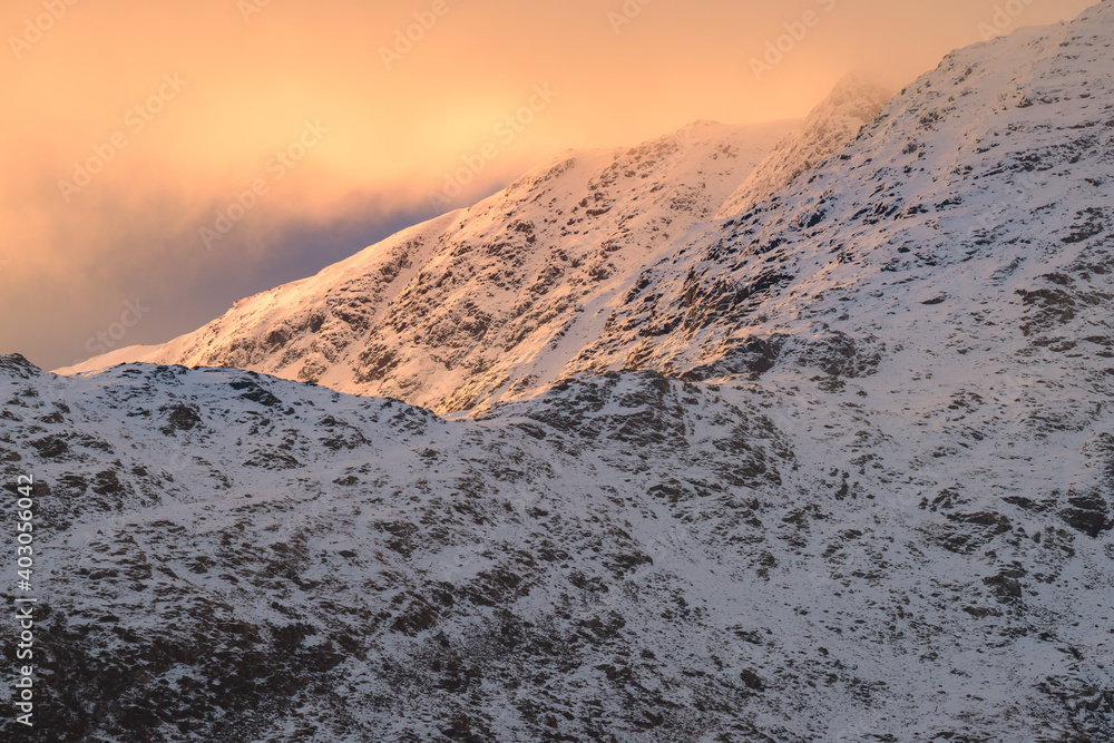 Morning sunlight on Winter snowcapped mountains in the Lake District with beautiful clouds.