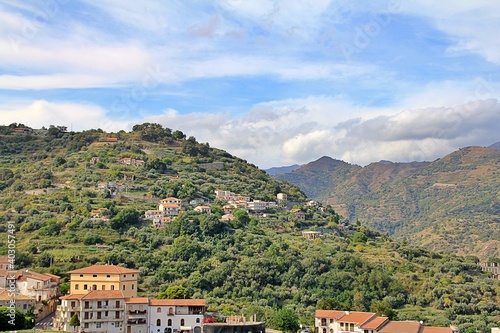 mountains, valleys, hills with vegetation and houses built on the hills, the sky with clouds, Sicily, Italy © AMTM