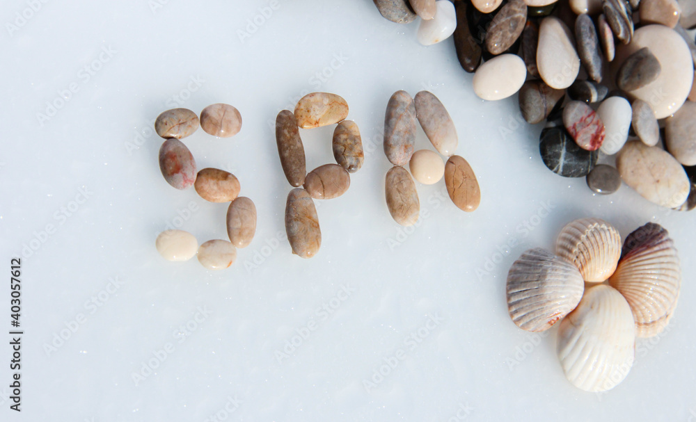 Sea pebble lettering: SPA. Marine background with seashells.