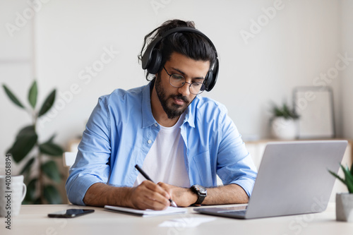 Distance Learning. Young Arab Guy In Headphones Studying With Laptop At Home photo